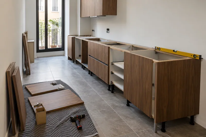 Visualización conceptual IA: Módulos de cocina en montaje con puertas pendientes de colocar.